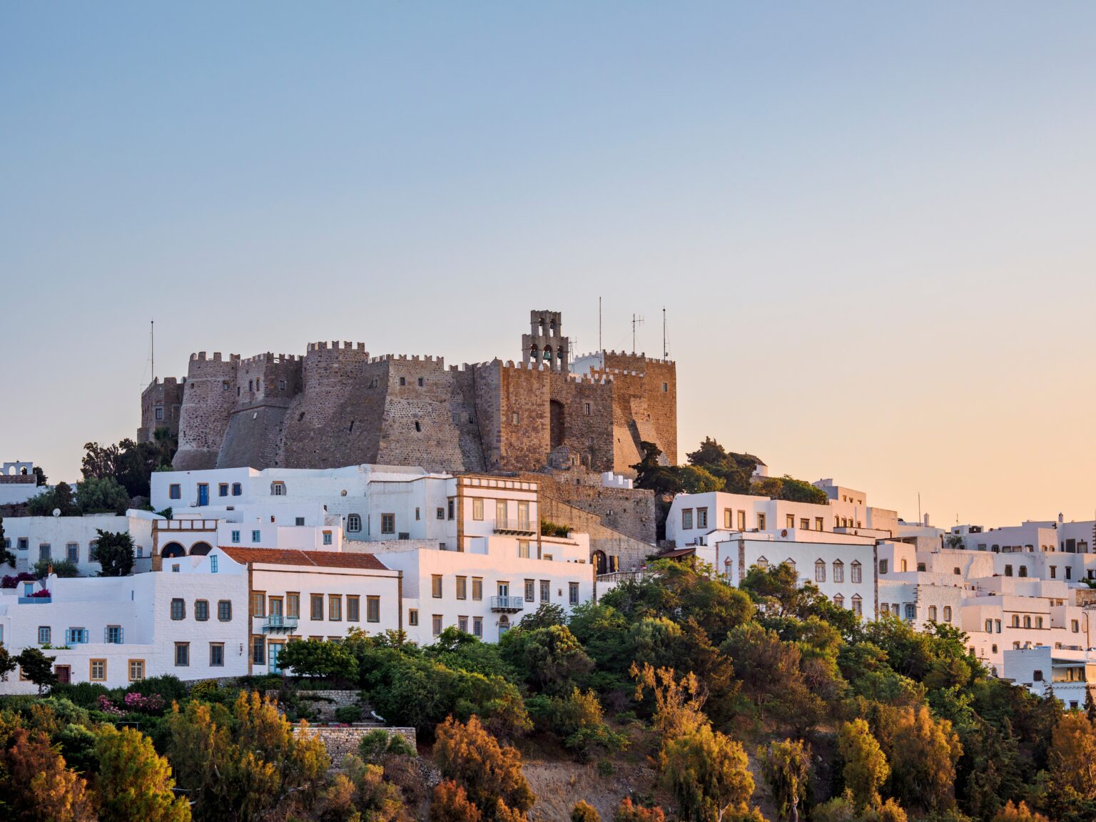 The Monastery of Saint John towering above whitewashed houses in Chora, Patmos at sunset.
