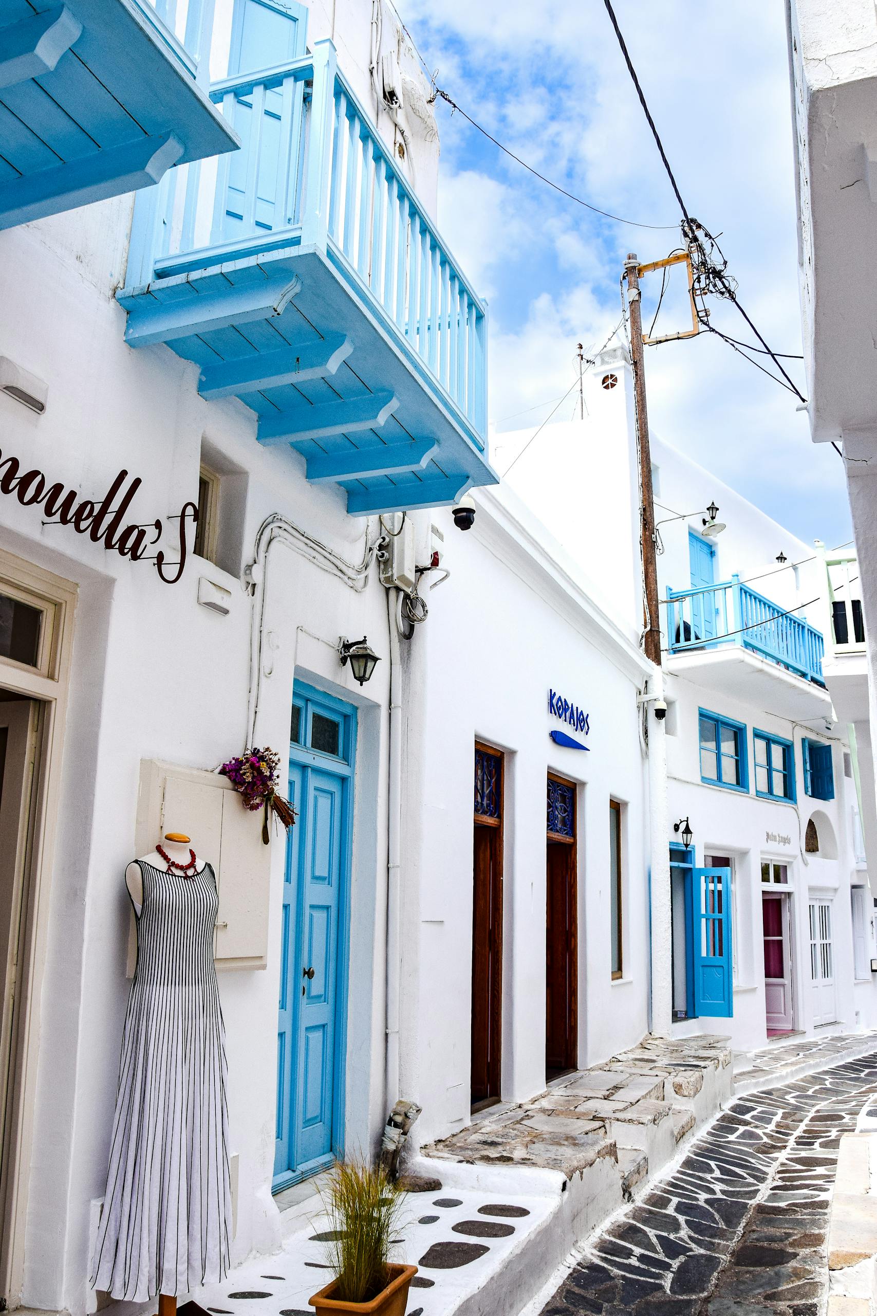 Picturesque narrow street in Mykonos, Greece, featuring iconic white and blue architecture.