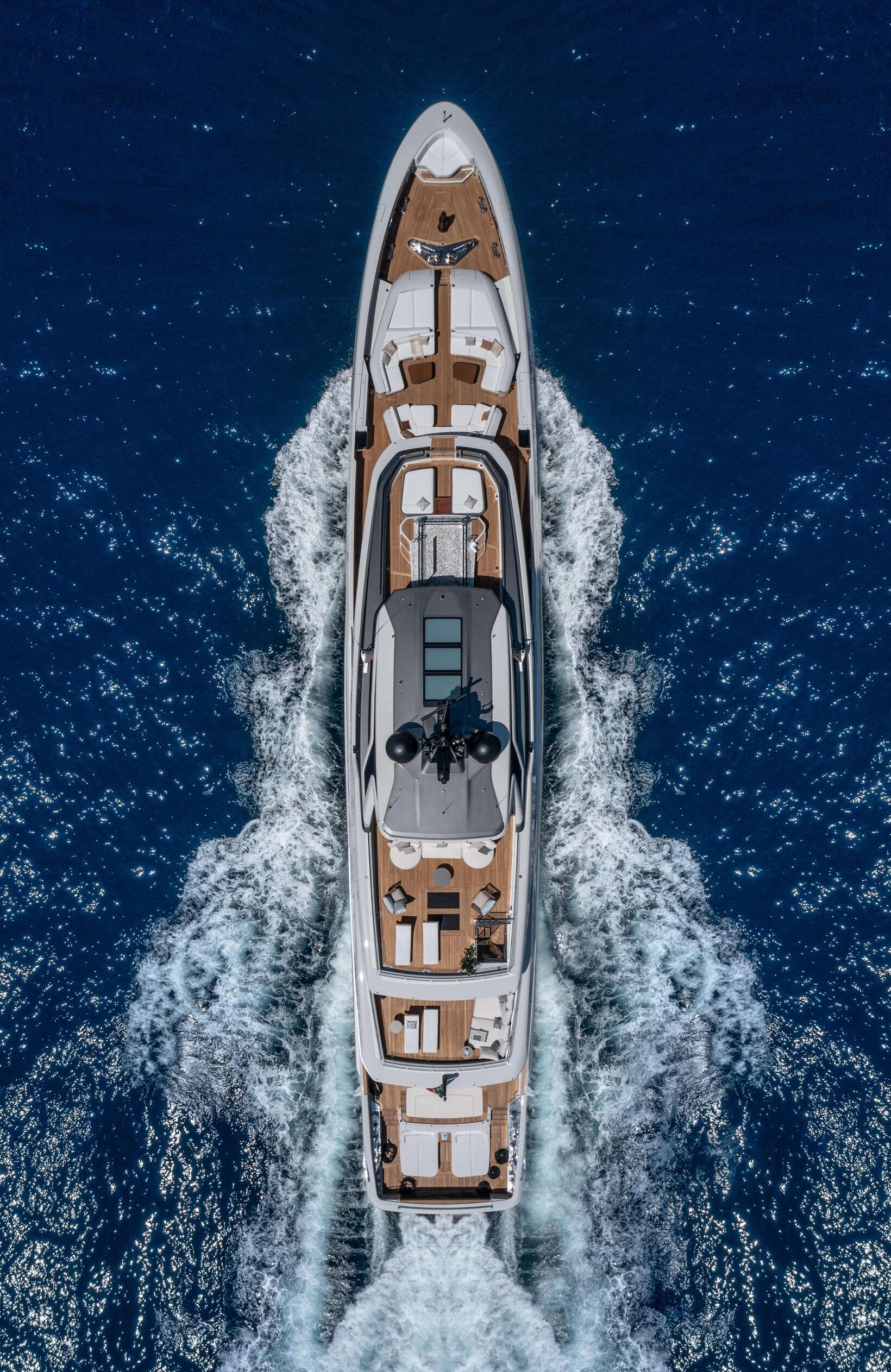 Aerial view of a luxury Baglietto T-Line 52m superyacht cruising through deep blue waters with a white foamy wake.