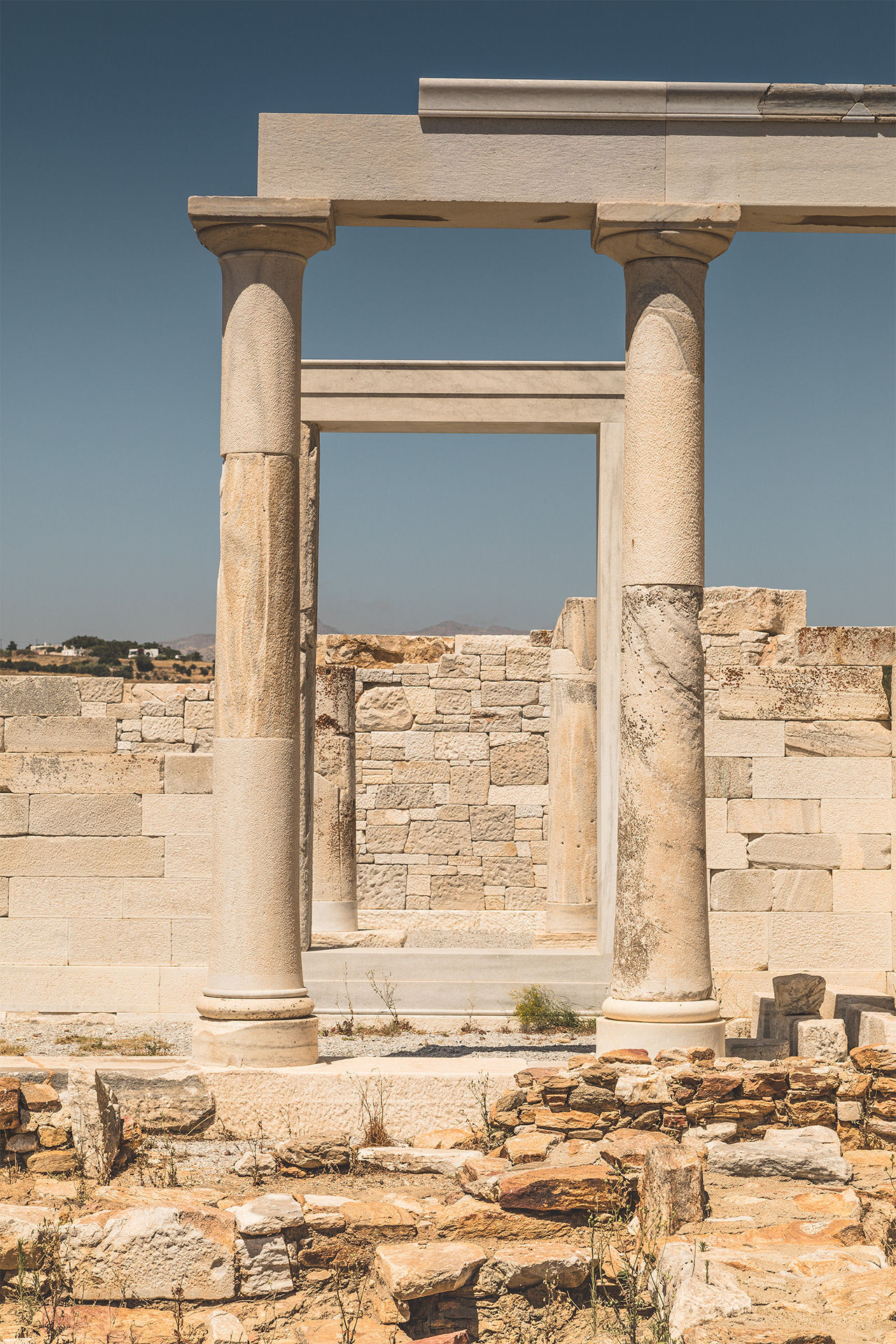Ruins of an ancient marble temple on Naxos, Greece, featuring classical columns and stone masonry under a clear blue sky.
