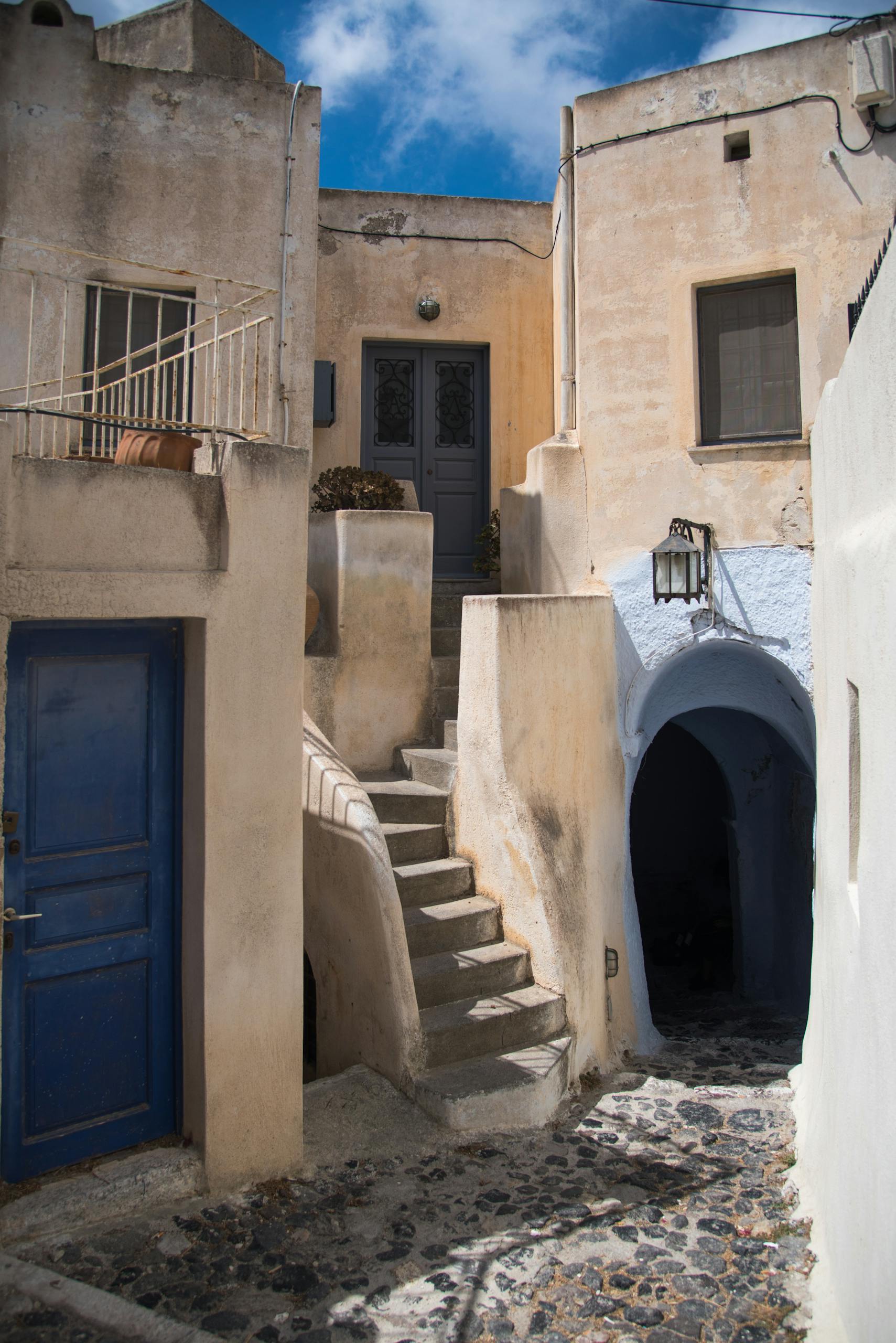Traditional Santorini architecture with blue doors and staircases in Pyrgos, Greece.