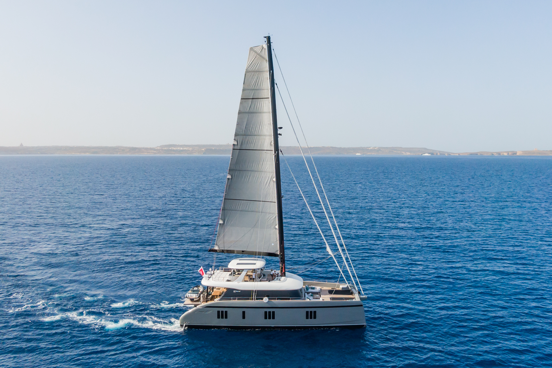 Luxury sailing catamaran JOY cruising through the Aegean Sea with sleek design and spacious deck